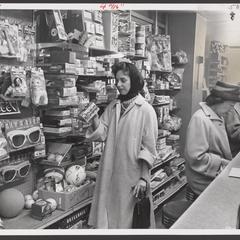 A woman views items in a toy display alongside a drugstore lunch counter