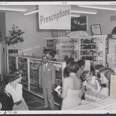 Customers gather at the prescription counter of a drugstore