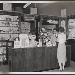 A pharmacist helps a customer at the prescription counter