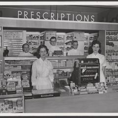 Pharmacy staff pose for a photo behind the prescription counter of a drugstore