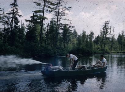 Men in motor boat emitting spray