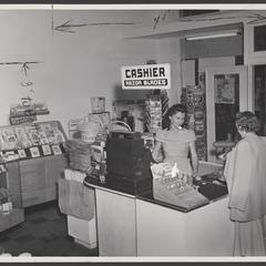 A shopper and a salesclerk stand at the checkout aisle of a drugstore
