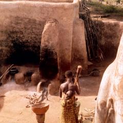 Woman Pounding Millet with Child on Her Back