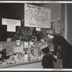 A woman and her young daughter look at a pharmacy window display