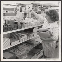 A young girl selects school supplies from a drugstore display