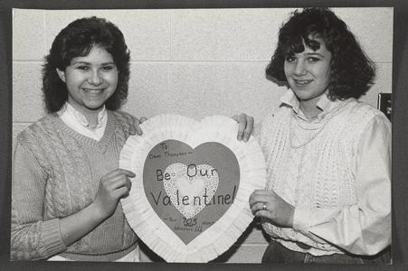 Two students posing with a valentine for Dean Robert Thompson