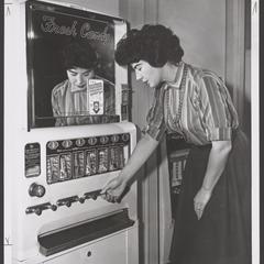 A woman selects candy from a vending machine