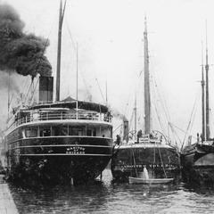 Stern view of the Manitou docked with two barges