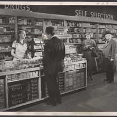 A salesclerk assists shoppers at a drugstore counter