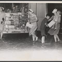 Woman and children stand in flood waters outside of a drugstore