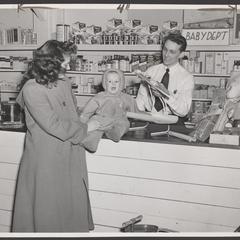 A pharmacy clerk assists a woman and her baby