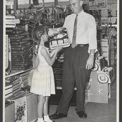 A salesclerk helps a young girl select school supplies