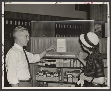 A pharmacist points a customer to air raid instructions
