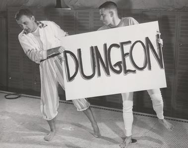 Two men hold a dungeon sign