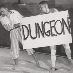 Two men hold a dungeon sign