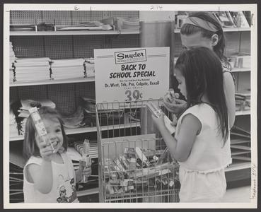 Young girls examine school supplies from a drugstore display