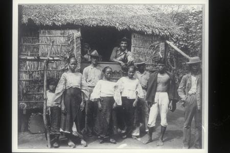 Two American soldiers visit with a group of Filipinos, early 1900s