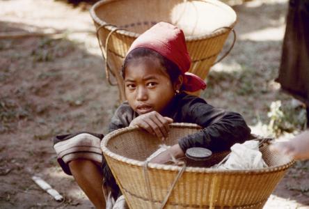 Khmu' girl is seated near her basket waiting to join other villagers on their way to the fields in Houa Khong Province