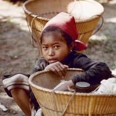 Khmu' girl is seated near her basket waiting to join other villagers on their way to the fields in Houa Khong Province