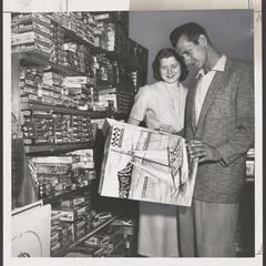 A man and a woman examine a boat model kit in a drugstore display