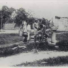 Filipino adults and children drinking and bathing at public fountain, early 1900s
