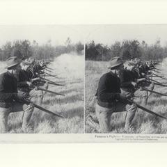 U.S. soldiers firing their rifles from a kneeling position in a field, 1899