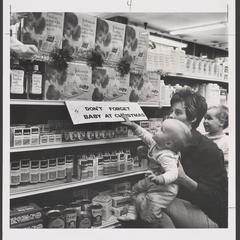 A woman and her young children view baby products in a drugstore display
