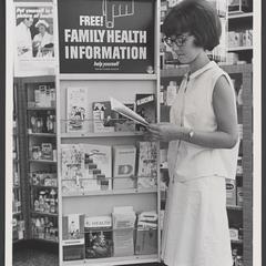 Woman reads pamphlet from Free Family Health Information display