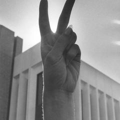 Anti-Vietnam War gathering, student showing peace symbol with raised hand