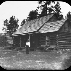 Man in front of log cabin