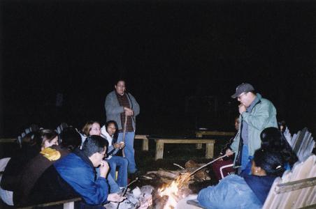 Students sit around a fire