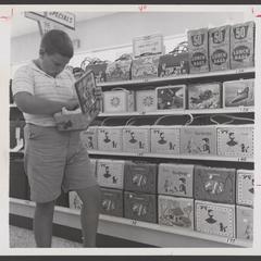 A young boy examines a lunch box from a drugstore display