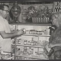 A pharmacist helps a young woman select a vitamin product